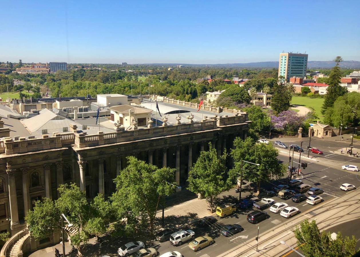 Hotel Stamford Plaza Adelaida Exterior foto The photo depicts a cityscape view, showcasing a mix of architectural structures and greenery. In the foreground, there is a large, classical building with columns, suggesting it may be a historical or governmental structure. Surrounding the building